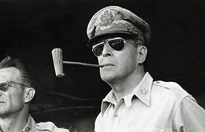 ** FILE ** Five star Gen. Douglas MacArthur smokes one of his trademark corn cob pipes aboard a ship bound for Luzon Island in the Philippines in this Jan. 20, 1945 file photo. A congressional committee cut Gen. MacArthur down to size in 1951, deftly exposing the flaws that had led President Harry Truman to remove him as Korean war commander. The man at left is unidentified. (AP Photo/File)